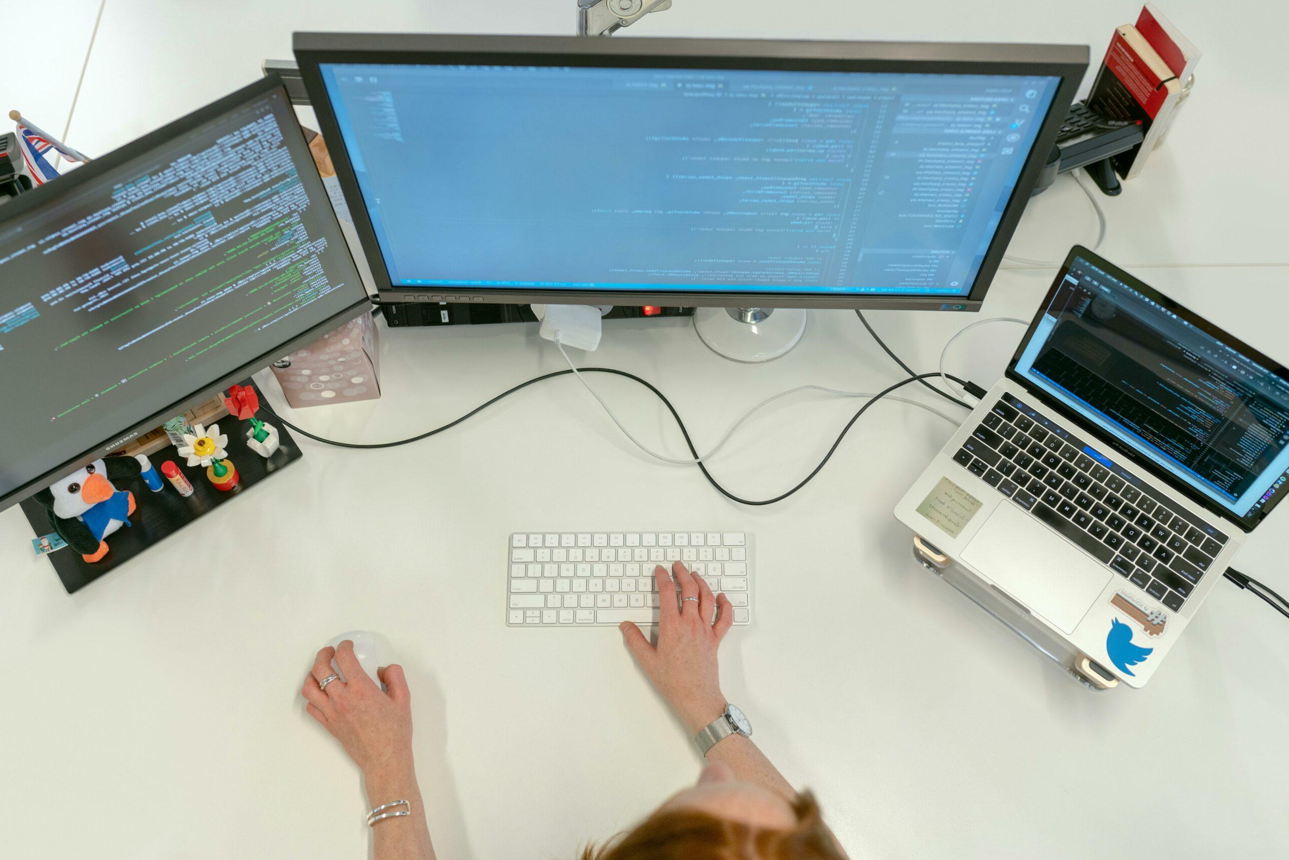 Woman using three computers at her workstation